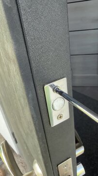 Handyman repairing a door lock with screwdriver