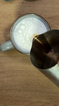 Barista pouring espresso coffee into milk foam