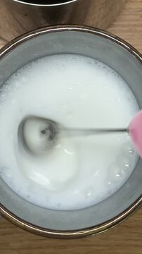 Barista using milk frother to foam milk for a cappuccino