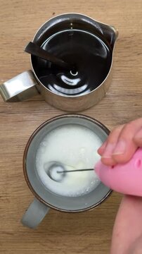 Woman preparing homemade coffee with milk frother