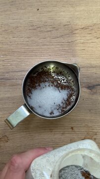 Person adding sugar to instant coffee grounds