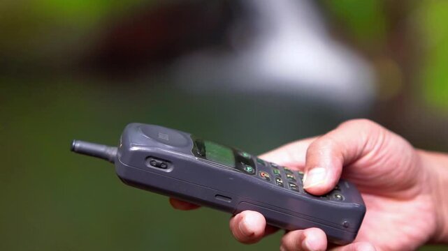 Operating a 90s mobile phone, a communication device that still relied on an antenna to pick up a signal.