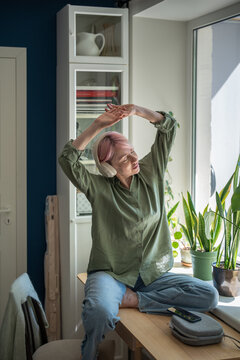 Carefree positive mature woman streaming music playlist on smartphone online and jamming to favorite song, relaxed smiling female enjoys listening tunes on app using digital mobile technology.