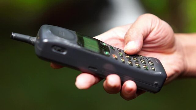 Operating a 90s mobile phone, a communication device that still relied on an antenna to pick up a signal.