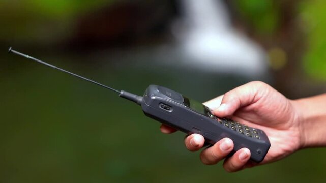 Operating a 90s mobile phone, a communication device that still relied on an antenna to pick up a signal.