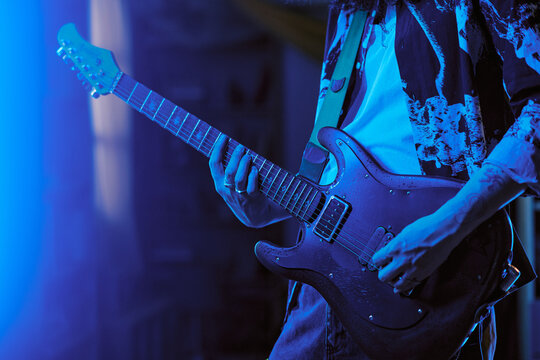 Close up of unrecognizable male rock musician playing electric guitar at home, practicing rock performance and creative lifestyle. Ideal for music lessons, streaming, artist branding