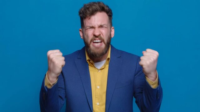 Furious angry businessman screaming with rage and clenching his fists against a blue background