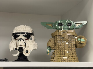 Obraz premium Lego star wars stormtrooper helmet and baby yoda figure displayed on a shelf in a home interior.