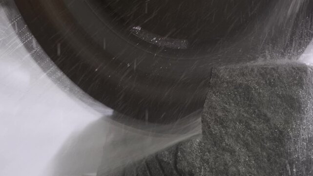 Industrial circular saw blade cutting a large granite block with water cooling in a stone processing factory