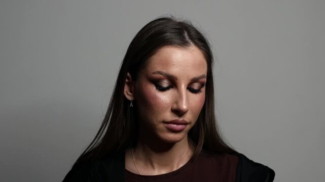 Woman applying false eyelashes during makeup routine in studio