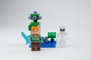 Obraz premium A Minecraft-style block toy character stands with a blue sword in front of a skeleton figure and fantasy toy structure on a white background on Apr 13, 2026 in Jakarta, Indonesia