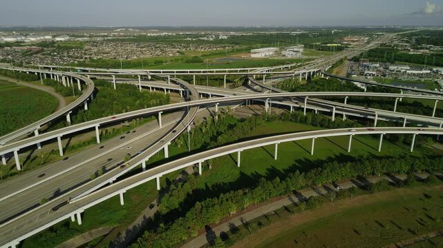 Aerial view of busy highway interchange with multiple elevated roads and smooth flowing traffic on sunny day.