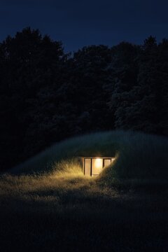 Eco-friendly earth-sheltered home illuminated at night with surrounding nature and trees