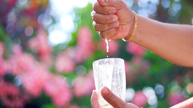 Fresh lime juice being squeezed into a clear glass, creating vibrant citrus splashes and droplets in bright natural sunlight. A refreshing scene highlighting natural ingredients, healthy beverages