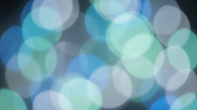 Abstract bokeh background with soft blue and green light circles. Dreamy out of focus lens flare texture. Ethereal glowing orbs for festive holiday design and creative overlays. 2026