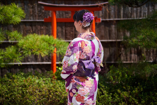 Woman in kimono facing torii gate