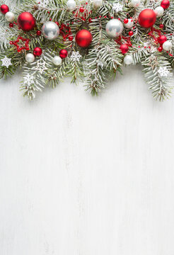 Snow-covered spruce branches  decorated with Christmas ornaments on old white wooden shabby board with empty space for text. Christmas and New Year background with holiday decorations. Flat lay