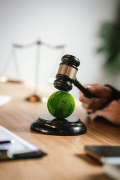 Judge's gavel above a green globe symbolizing environmental law, ESG compliance, climate justice, and sustainable governance.