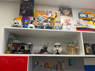 Obraz premium A shelf filled with lego models, star wars figures and toy boxes in a bright room, showing a colorful collector display.