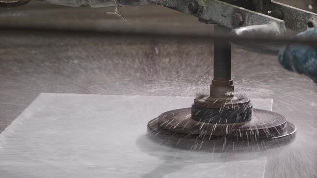Industrial worker polishing a marble slab with a grinding machine in a stone factory