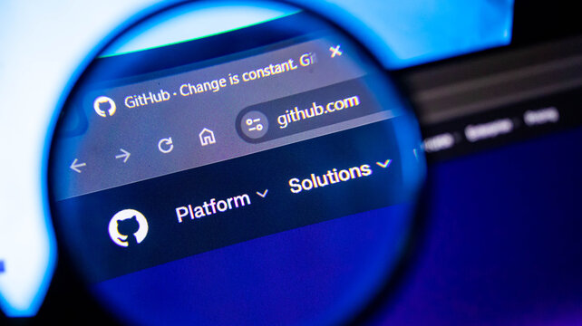 Magnifying glass focused on github website logo on computer monitor.