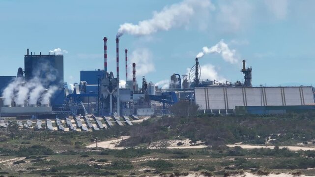 Industrial factory smokestacks emitting pollution near the coast
