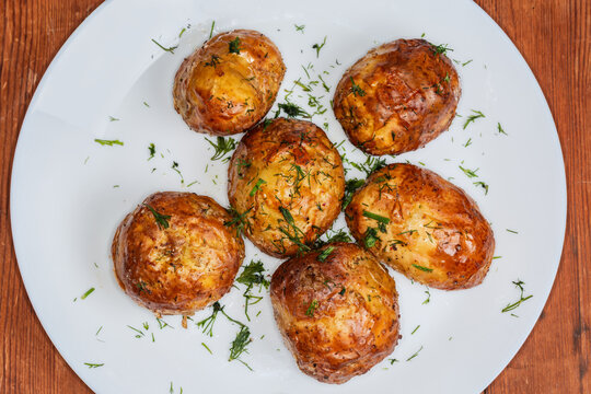 Baked young potatoes on dish on rustic table, top view