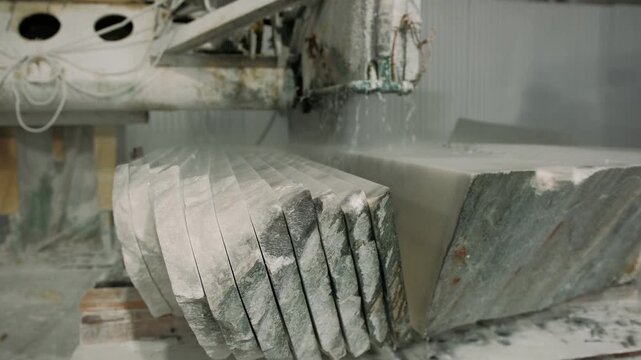 Industrial circular saw machine cutting marble block into multiple slabs in a factory