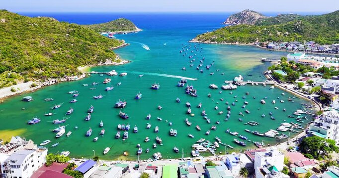 Breathtaking aerial view of Vinh Hy Bay, Vietnam, featuring emerald waters, colorful fishing boats, coastal villages, and rugged mountains