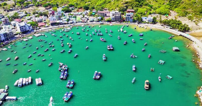 Breathtaking aerial view of Vinh Hy Bay, Vietnam, featuring emerald waters, colorful fishing boats, coastal villages, and rugged mountains