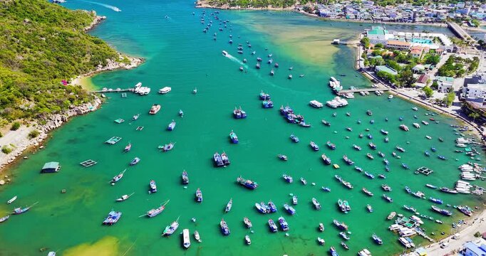 Breathtaking aerial view of Vinh Hy Bay, Vietnam, featuring emerald waters, colorful fishing boats, coastal villages, and rugged mountains