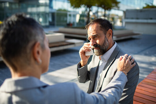 Coworker comforting emotional businessman in office courtyard