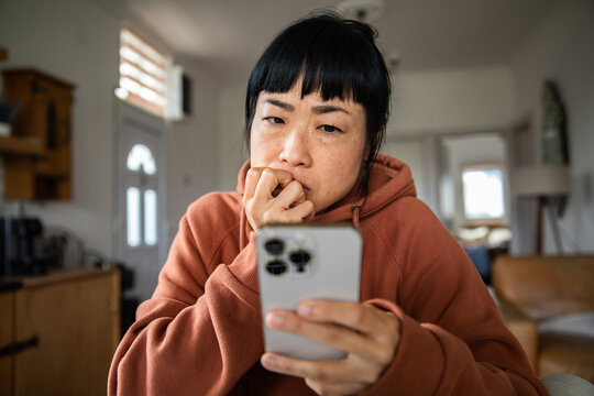 Concerned woman reading smartphone message at home