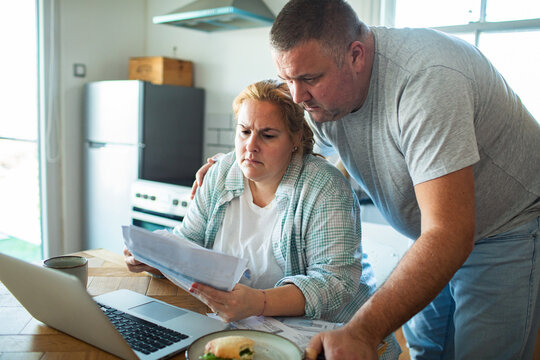 Worried couple reviewing household bills at kitchen table