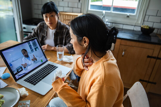 Sick woman consulting online doctor in home kitchen