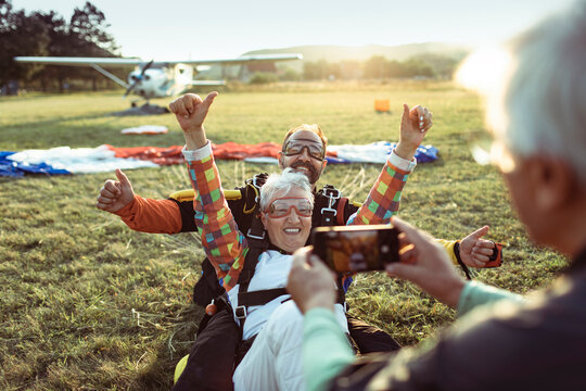 Senior woman celebrates tandem skydive landing at airfield
