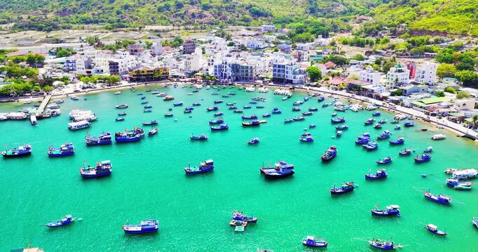 Breathtaking aerial view of Vinh Hy Bay, Vietnam, featuring emerald waters, colorful fishing boats, coastal villages, and rugged mountains