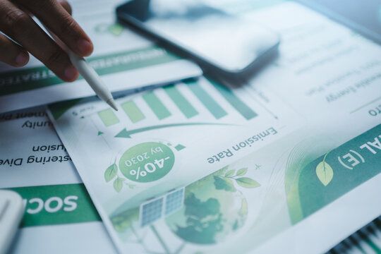 ESG report emission reduction carbon footprint sustainability goals net zero 2030 strategy, pointing stylus at environmental chart tracking performance green corporate responsibility climate action