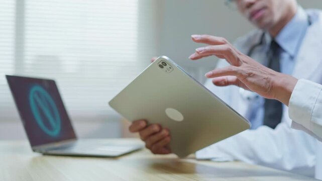 Doctors consulting together in a modern medical office, reviewing information on a tablet and computer for medical research, telehealth planning, healthcare technology, and collaborative clinical disc