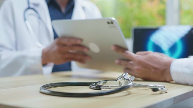 Doctors consulting together in a modern medical office, reviewing information on a tablet and computer for medical research, telehealth planning, healthcare technology, and collaborative clinical disc