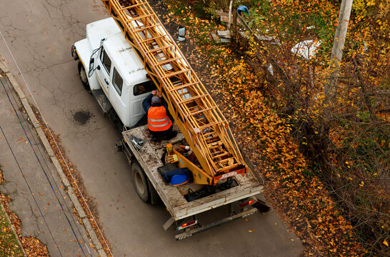 Worker in reflective vest fixing a mobile crane on a truck in autumn, construction and maintenance work concept. Professional construction worker in a reflective vest operating a mobile crane truck