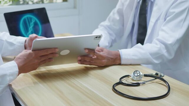 Doctors consulting together in a modern medical office, reviewing information on a tablet and computer for medical research, telehealth planning, healthcare technology, and collaborative clinical disc