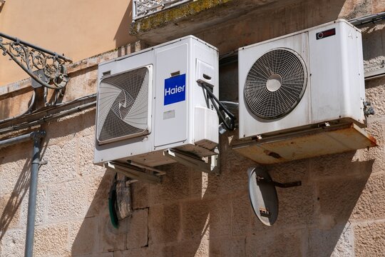 CORATO, ITALY - APRIL 23, 2026: Haier and Riello brand air conditioning external unit mounted on a wall of a building in Corato, Italy.