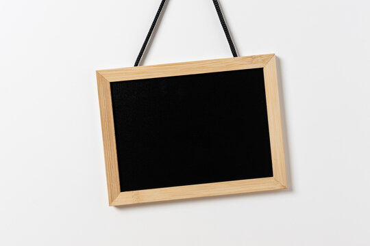 Blank blackboard with wooden frame hanging on white wall. Template mockup