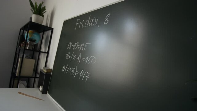 Green chalkboard with handwritten math equations hanging on classroom wall. Footage for educational marketing, online tutoring ads, and school curriculum promotions