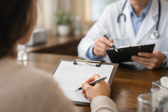 Patient signs medical consent documents as physician provides guidance during healthcare consultation, highlighting informed decision making, patient care and clinical communication with copy space.