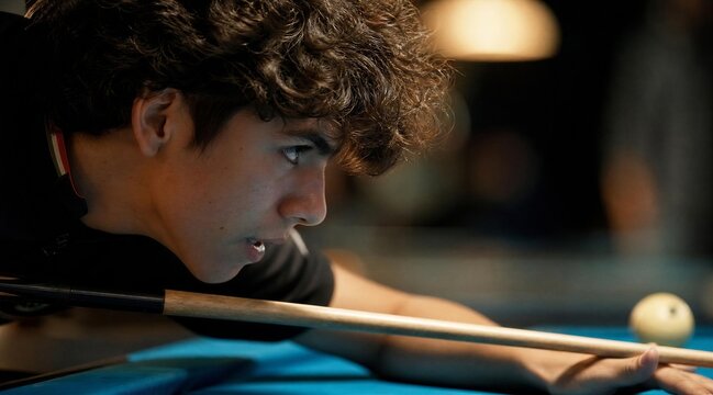 Player aiming pool cue at billiard ball