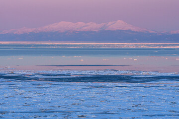Drift ice and the Shiretoko mountain range with Mount Rausu glowing at sunset seen from Abashiri, Hokkaido, Japan © ibuki