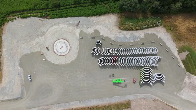 Construction site, preparation for building wind turbine farm, concrete tower section, foundation area, rows of curved segments, gravel ground in forest, Germany