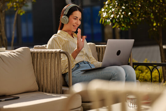 Woman on video call working remotely at outdoor cafe